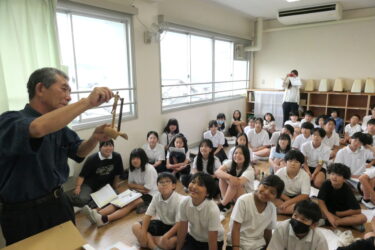 小林さんが制作した竹細工に見入る児童たち＝岡山県津山市で
