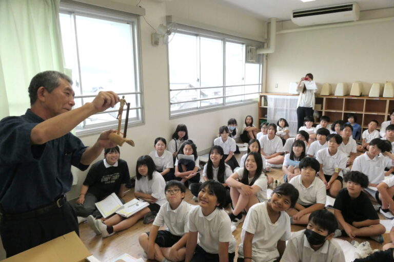 小林さんが制作した竹細工に見入る児童たち＝岡山県津山市で