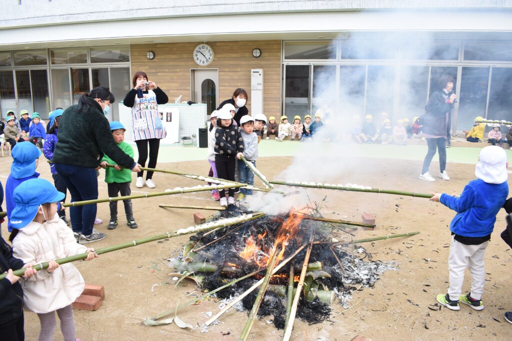 竹に挟んだ餅を焼く子どもたち=岡山県津山市の城西保育園で