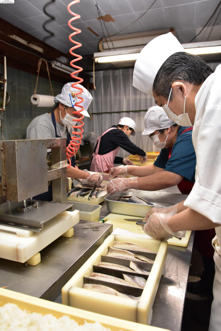 手際よく鯖寿司をつくる榎本代表ら=岡山県津山市で