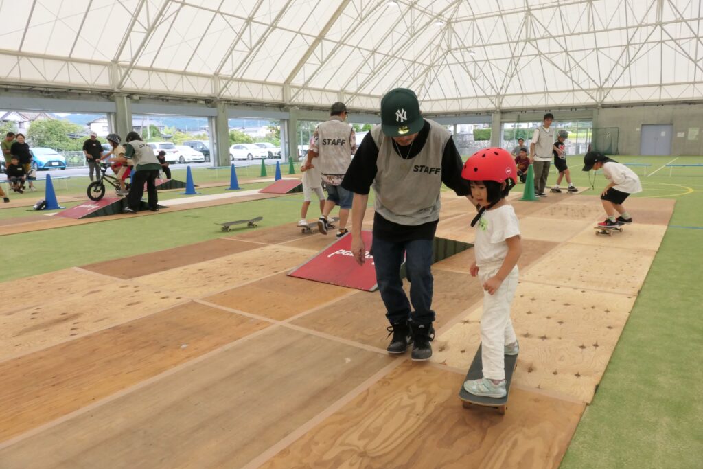 スタッフの補助を受けながらスケートボードを楽しむ子どもたち