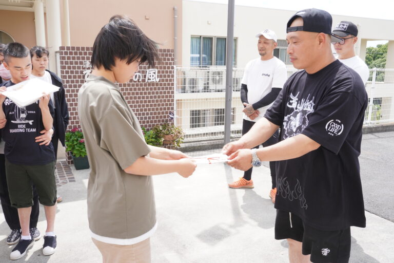 施設の子どもに寄付金の目録を手渡すメンバーの4PRIDEさん（右）=岡山県津山市で