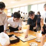 大豆を箸でつまんで運ぶゲームを楽しむ生徒