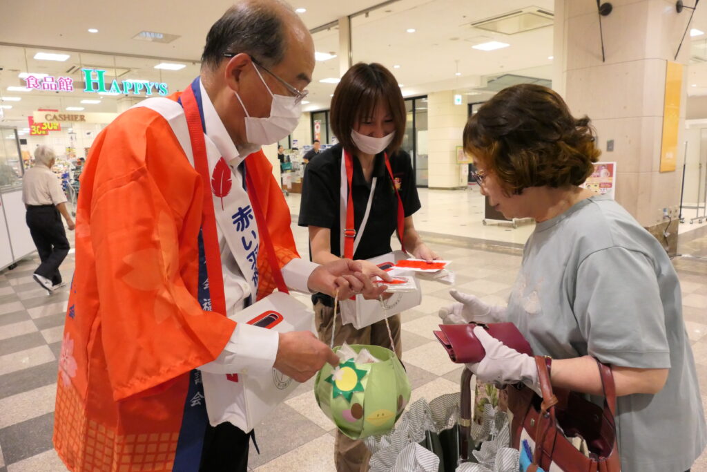 赤い羽根を受け取る買い物客