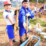 収穫した自然薯を手に笑顔の児童＝岡山県津山市で