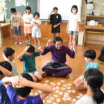 昔遊びを楽しむ留学生と児童=岡山県津山市で