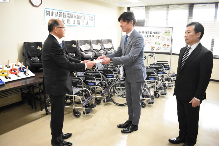 寄贈品の前で目録を手渡す金沢支部長=岡山県津山市山北の市総合福祉会館で