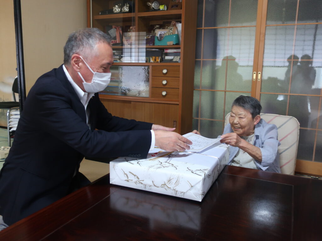 祝い状と記念品を手に笑顔の福田さん