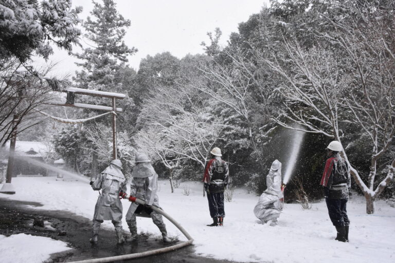 雪が降る中、消火訓練を行う消防団員=岡山県津山市で