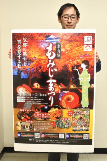 「津山城もみじまつり」のポスターを手にPRする市観光協会の職員=岡山県津山市で