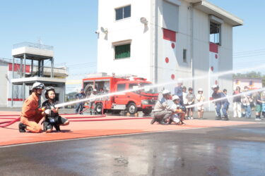 消防職員に支えられながら放水体験に挑戦する子どもたち＝岡山県津山市で