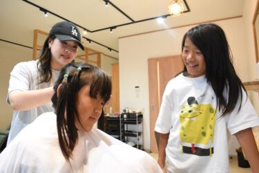 頭髪を寄付するため、2年半伸ばし続けた髪を切ってもらう保田優君（右）と弟の佑君=岡山県津山市で