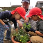 高校生に教わりながら鉢に花を植える園児=岡山県真庭市で