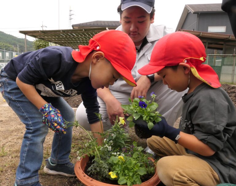 高校生に教わりながら鉢に花を植える園児=岡山県真庭市で