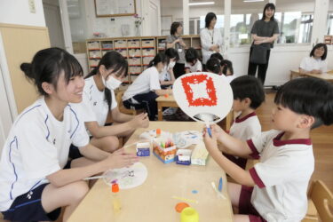 会話を弾ませながら園児とうちわを作る高校生=岡山県津山市、総社保育園で