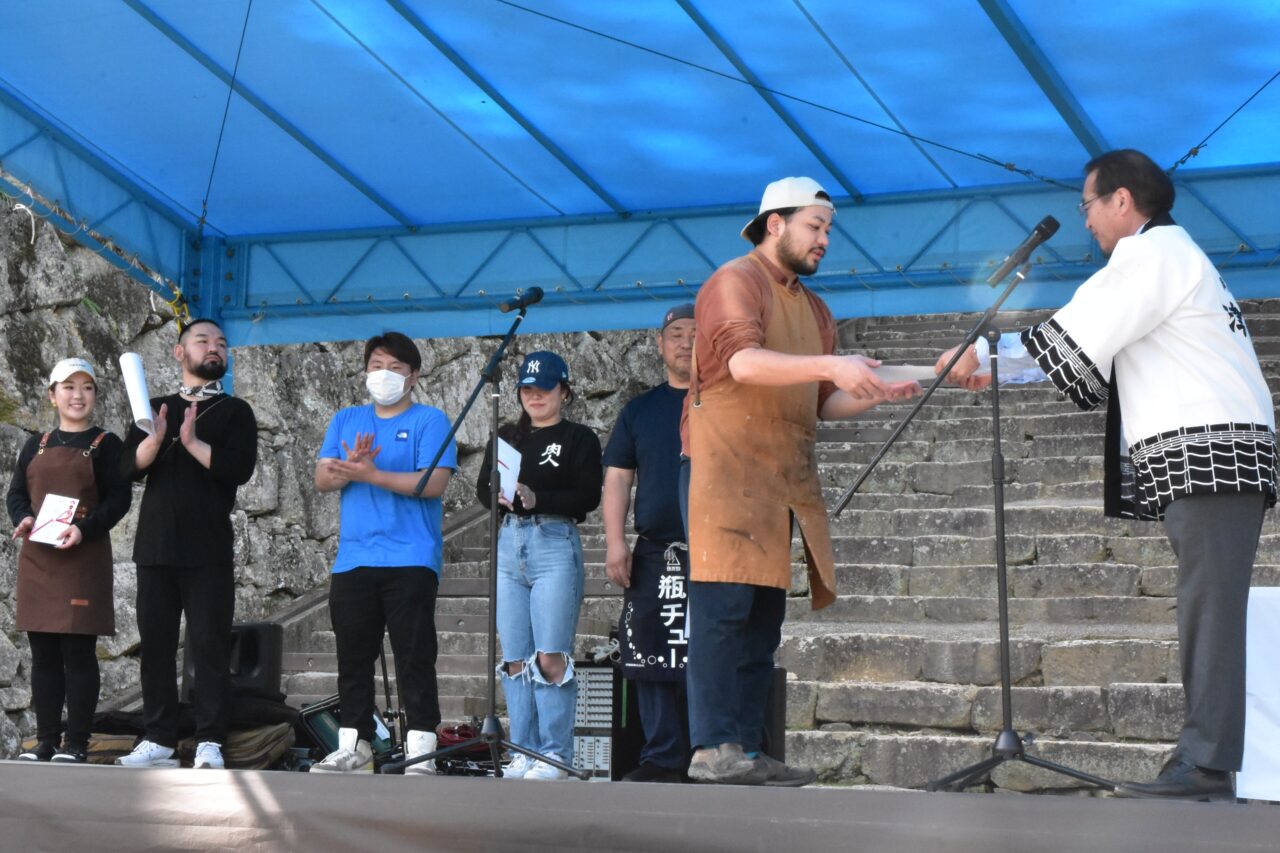 表彰状を受け取る、初優勝に輝いた鉄板食堂りべるたあぱんだの安達さん＝岡山県津山市で