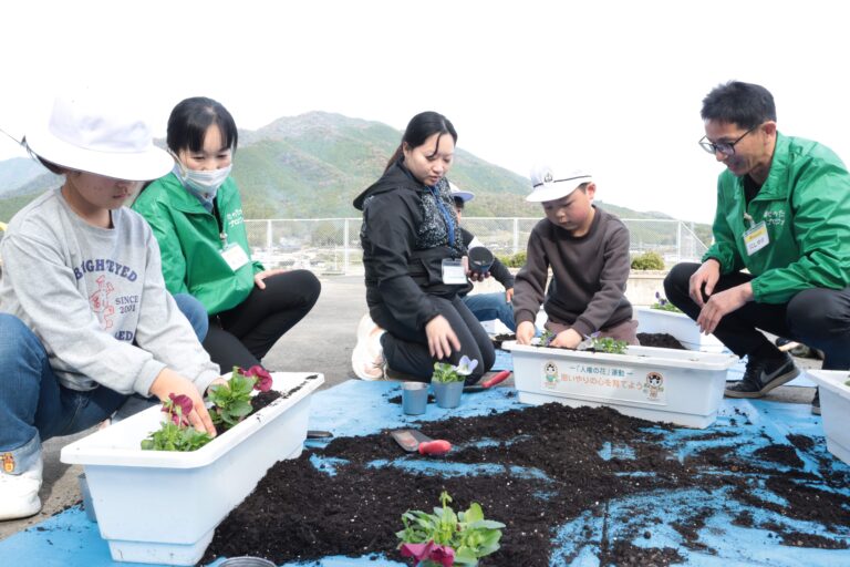 社員らとパンジーを植える児童=岡山県津山市で