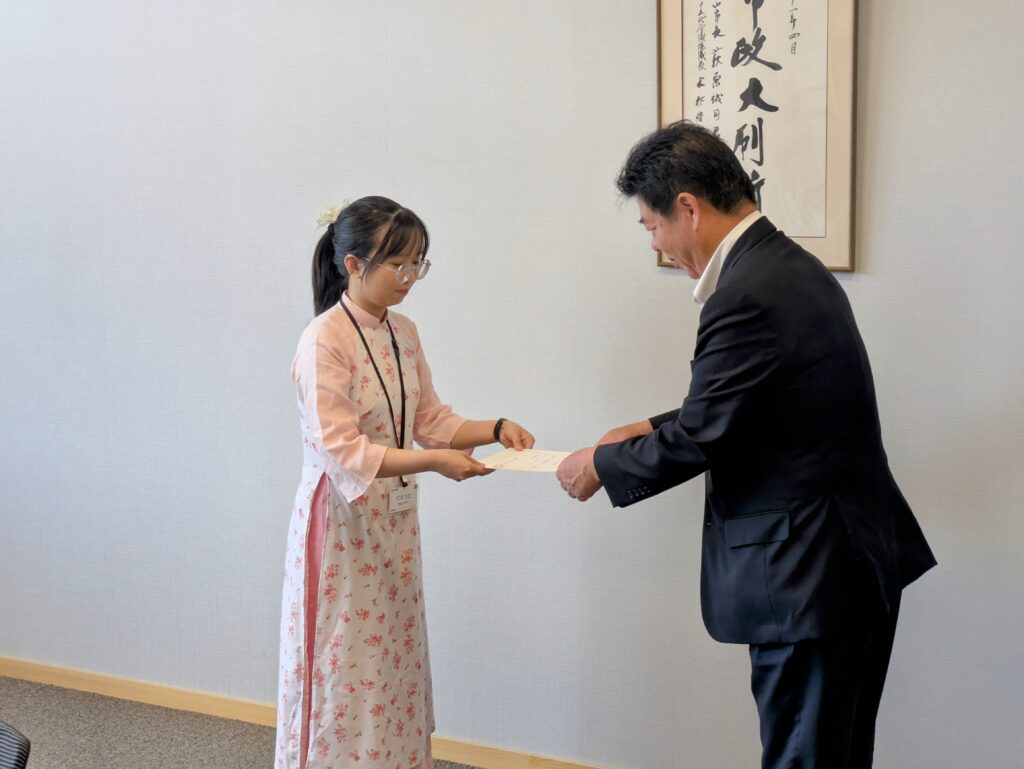 萩原市長から任用通知書を受け取るグエットさん