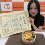 賞状を手にする佐子さんと受賞したミマダイン弁当=岡山県津山市で