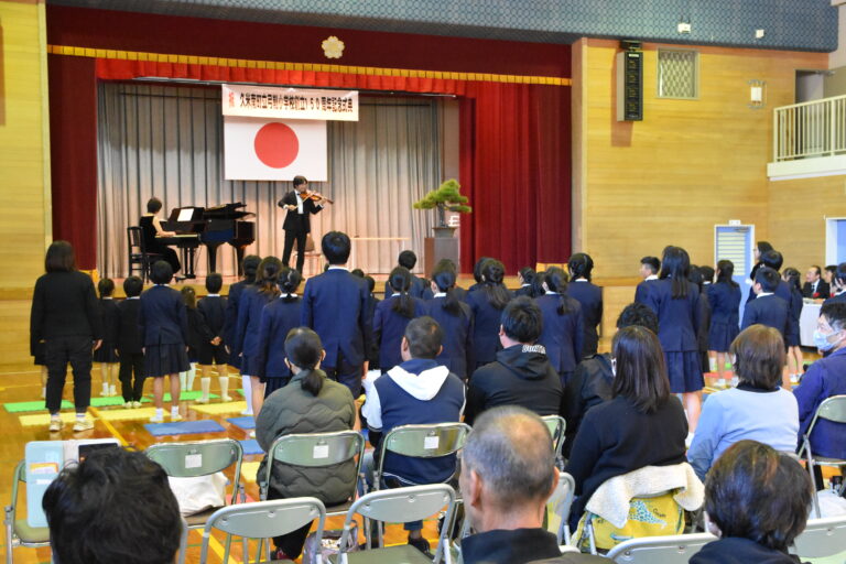 卒業生の入江さんの演奏で校歌を歌い上げる児童=岡山県久米南町で