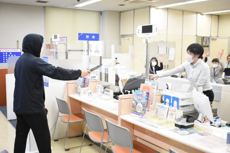 刃物で脅し、現金を奪おうとする犯人役=岡山県津山市で