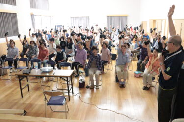 重りを手に「こけない体操」に取り組む参加者＝岡山県津山市で
