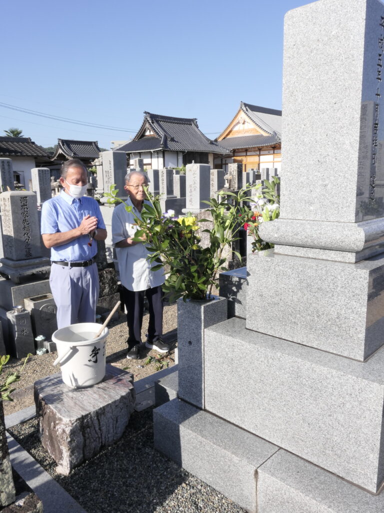 祖先の墓の前で手を合わせる人たち=岡山県津山市、愛染寺で