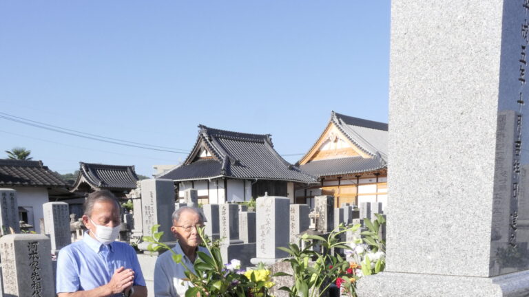 祖先の墓の前で手を合わせる人たち=岡山県津山市、愛染寺で