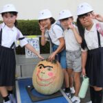巨大カボチャを囲んで笑顔を見せる高田小の児童たち＝岡山県津山市で