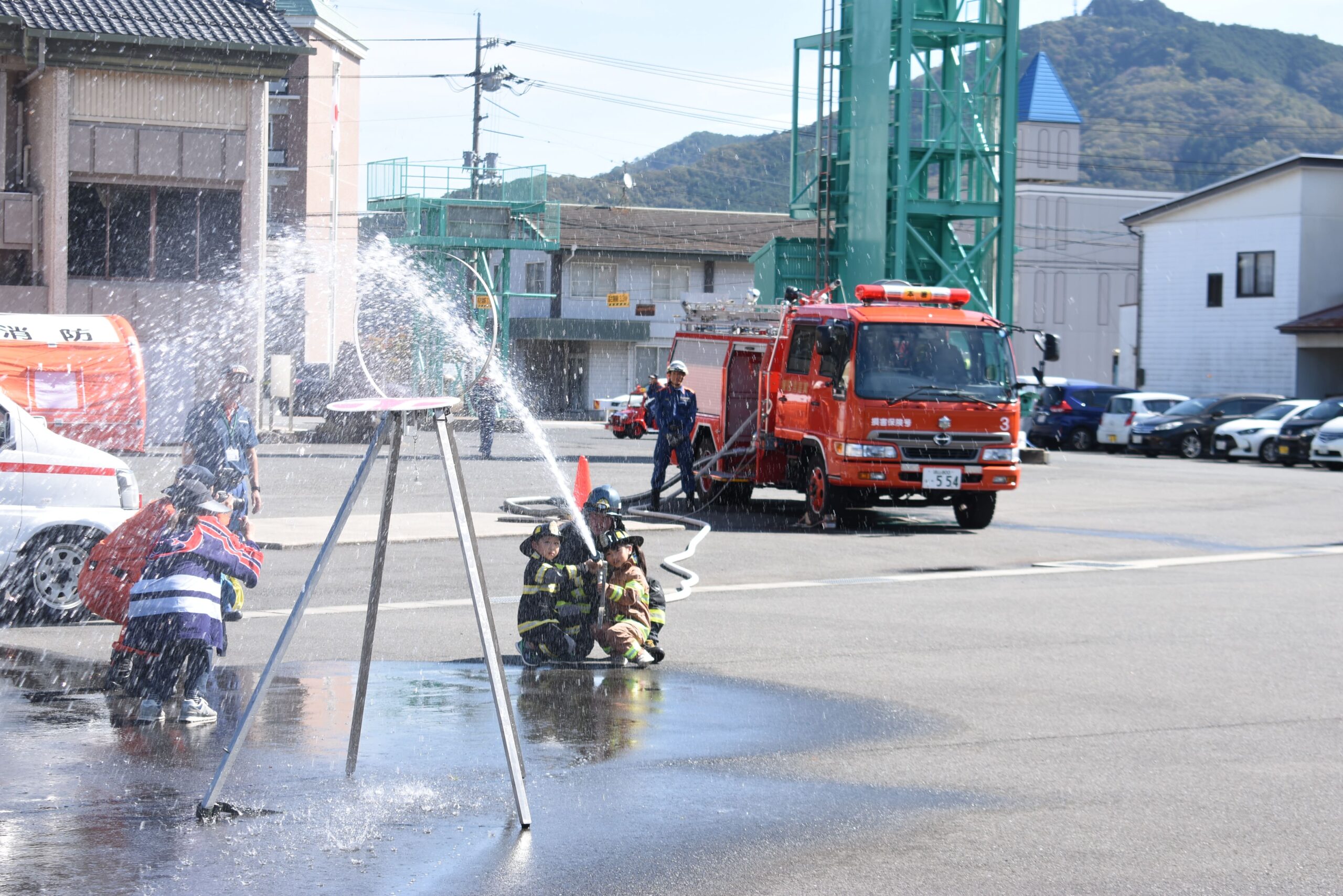 消防士に教わりながら的を目がけ放水する子どもたち