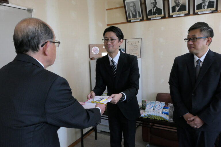 目録を手渡す小林ストアマネージャーと長谷川ストアマネージャー=岡山県津山市で