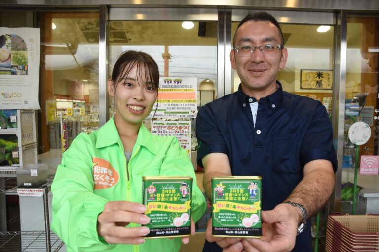 啓発キャンデー「ロマンスあめ」を手にする田邊社長と県の担当者=岡山県津山市、道の駅・久米の里で