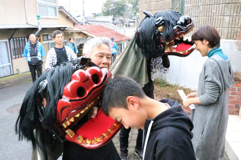 獅子に頭をかんでもらい厄払いしてもらう親子=岡山県津山市で